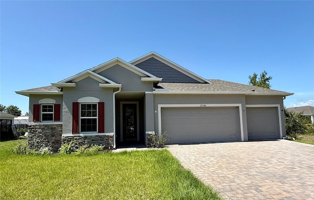 27206 Adams St, Punta Gorda, FL 33983 - view of front of home featuring a garage, decorative driveway, a front lawn, stucco siding, and stone siding