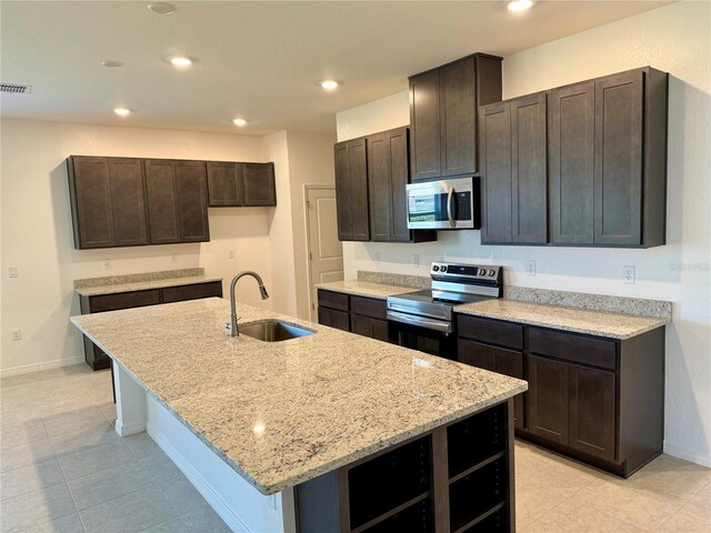 27206 Adams St, Punta Gorda, FL 33983 - kitchen featuring stainless steel appliances, a sink, dark brown cabinets, an island with sink, and light stone countertops
