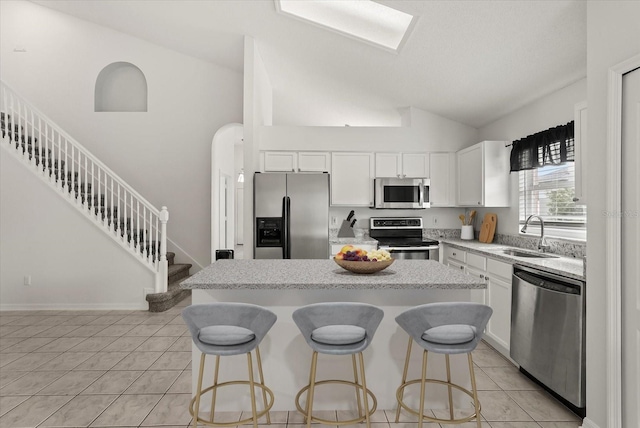 4249 Andover Cay Blvd, Orlando, FL 32825 - kitchen featuring stainless steel appliances, a sink, light tile patterned floors, vaulted ceiling, and a breakfast bar