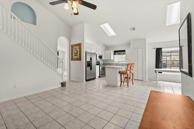 4249 Andover Cay Blvd, Orlando, FL 32825 - kitchen featuring stainless steel appliances, a breakfast bar area, light tile patterned floors, ceiling fan, and arched walkways
