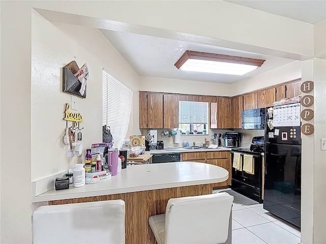 1748 Foxhall Cir Unit 1748, Kissimmee, FL 34741 - kitchen featuring black appliances, a peninsula, brown cabinets, light countertops, and a sink