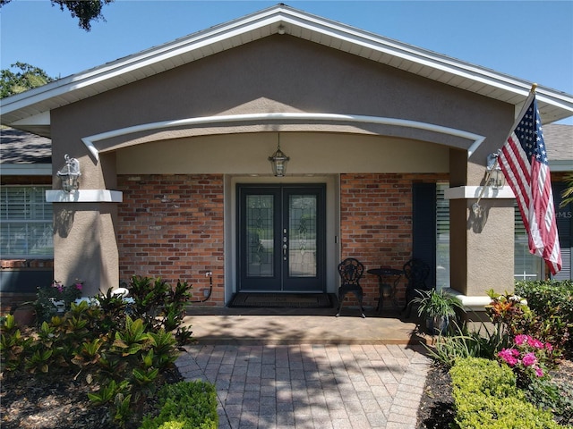 5127 Leeward Way, Orlando, FL 32809 - doorway to property with stucco siding, a porch, brick siding, and french doors