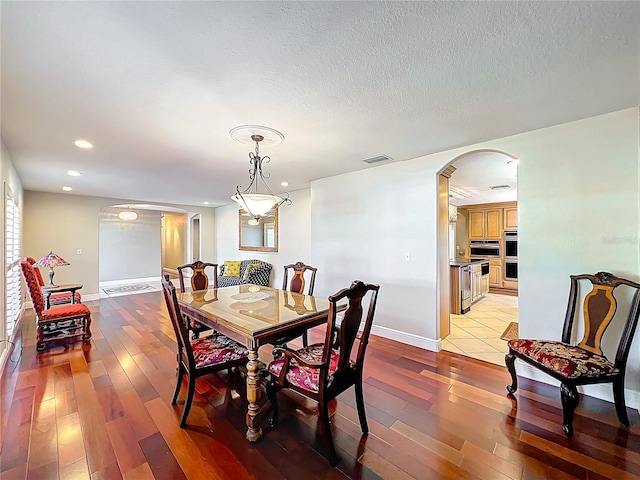 5127 Leeward Way, Orlando, FL 32809 - dining area with arched walkways, light wood-style floors, recessed lighting, baseboards, and a textured ceiling