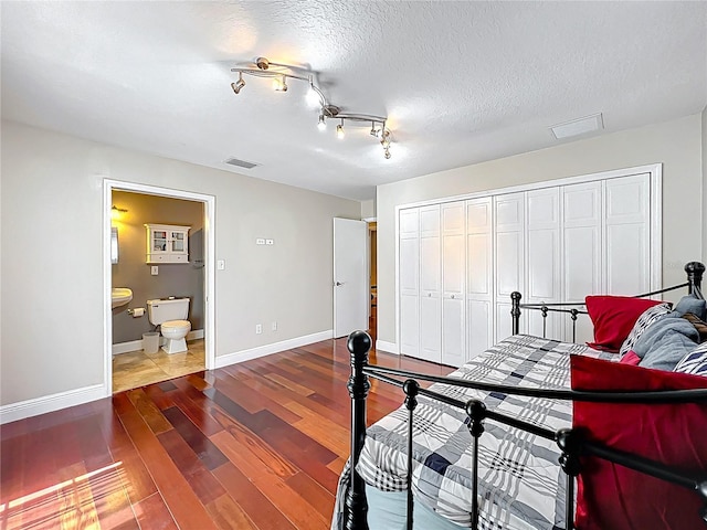 5127 Leeward Way, Orlando, FL 32809 - bedroom with dark wood-style flooring, a closet, baseboards, ensuite bath, and a textured ceiling