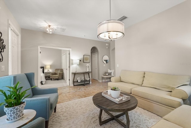 living area featuring arched walkways and light tile patterned floors