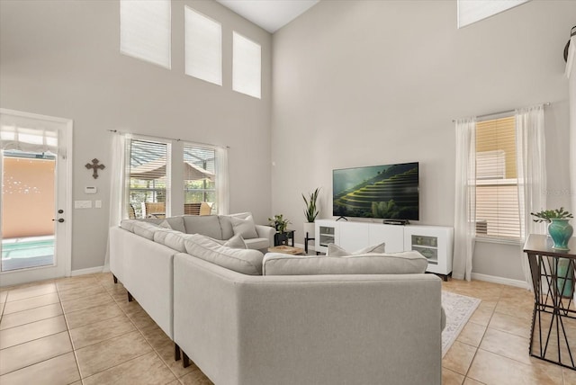 living area with a towering ceiling, light tile patterned floors, and baseboards