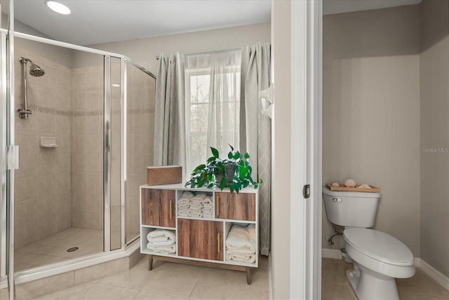 full bathroom with a stall shower, tile patterned floors, toilet, and baseboards