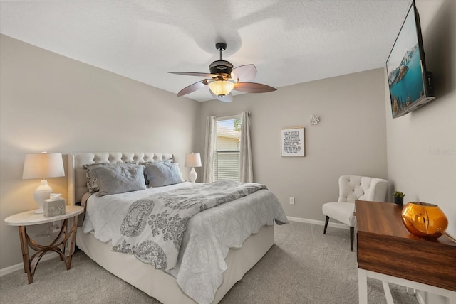 bedroom featuring light colored carpet, baseboards, ceiling fan, and a textured ceiling