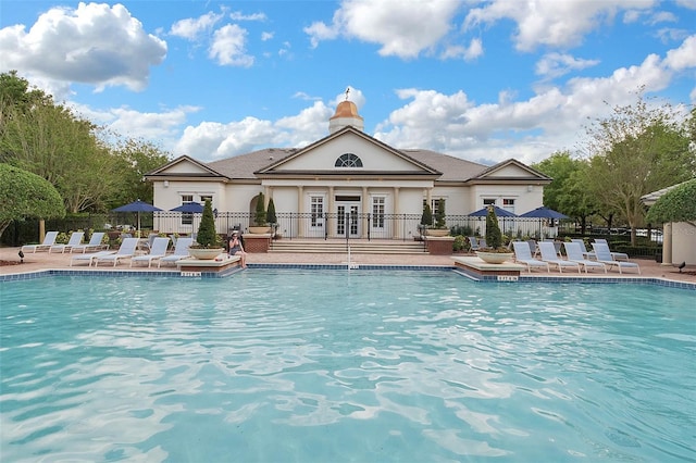 community pool featuring french doors, fence, and a patio