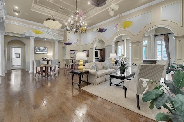 living area with decorative columns, healthy amount of natural light, ornamental molding, a high ceiling, and wood-type flooring