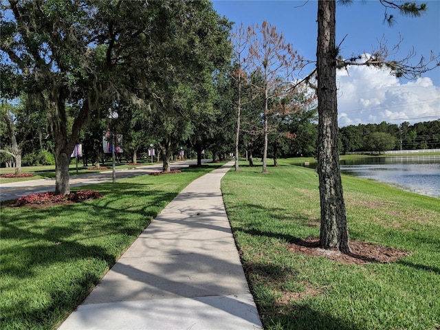 surrounding community with a water view and a yard