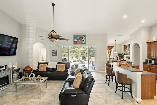 3451 Players Point Loop, Apopka, FL 32712 - living room with arched walkways, ceiling fan, high vaulted ceiling, baseboards, and a fireplace
