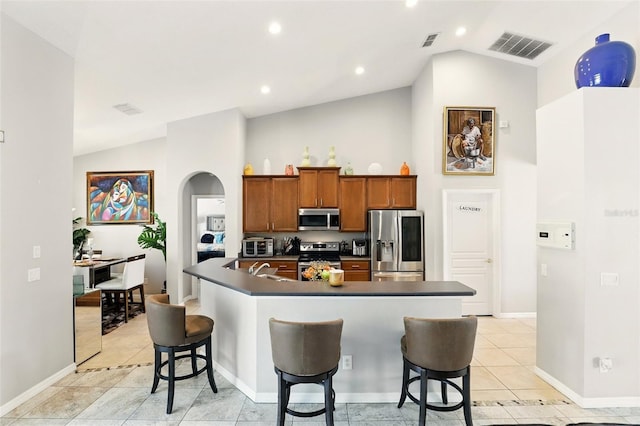 3451 Players Point Loop, Apopka, FL 32712 - kitchen with stainless steel appliances, dark countertops, arched walkways, a kitchen breakfast bar, and brown cabinets