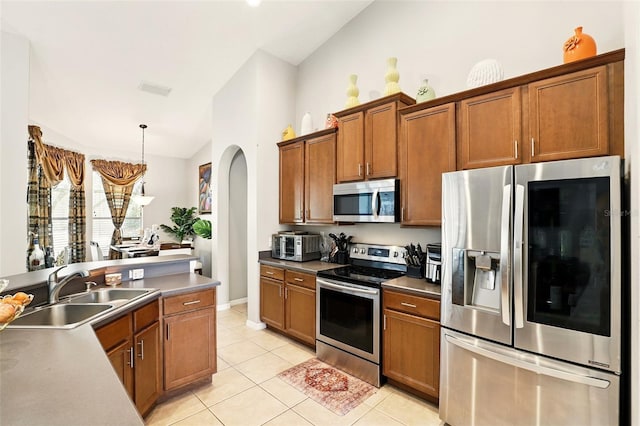 3451 Players Point Loop, Apopka, FL 32712 - kitchen featuring appliances with stainless steel finishes, a sink, arched walkways, brown cabinetry, and lofted ceiling