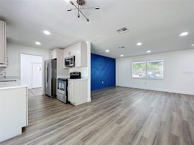1307 Jean Ct, Eustis, FL 32726 - kitchen with stainless steel appliances, light wood finished floors, a textured ceiling, open floor plan, and light countertops