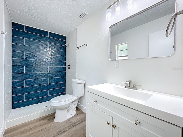 1307 Jean Ct, Eustis, FL 32726 - bathroom with toilet, wood finished floors, tiled shower, vanity, and a textured ceiling