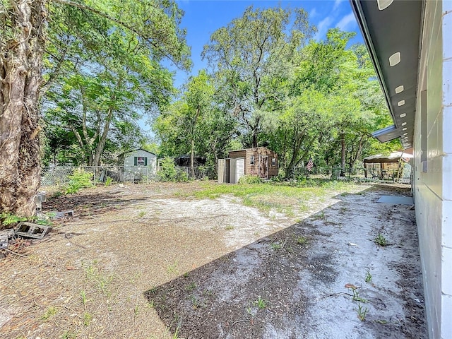 1307 Jean Ct, Eustis, FL 32726 - view of yard featuring a storage unit, fence, an outbuilding, and view of wooded area