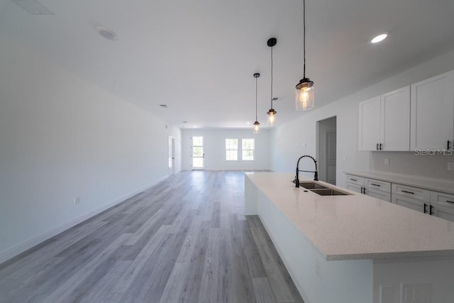 13419 SW 77th Ave, Ocala, FL 34473 - kitchen featuring a sink, white cabinetry, light wood finished floors, a center island with sink, and open floor plan