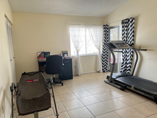 workout room with a textured ceiling and light tile patterned floors