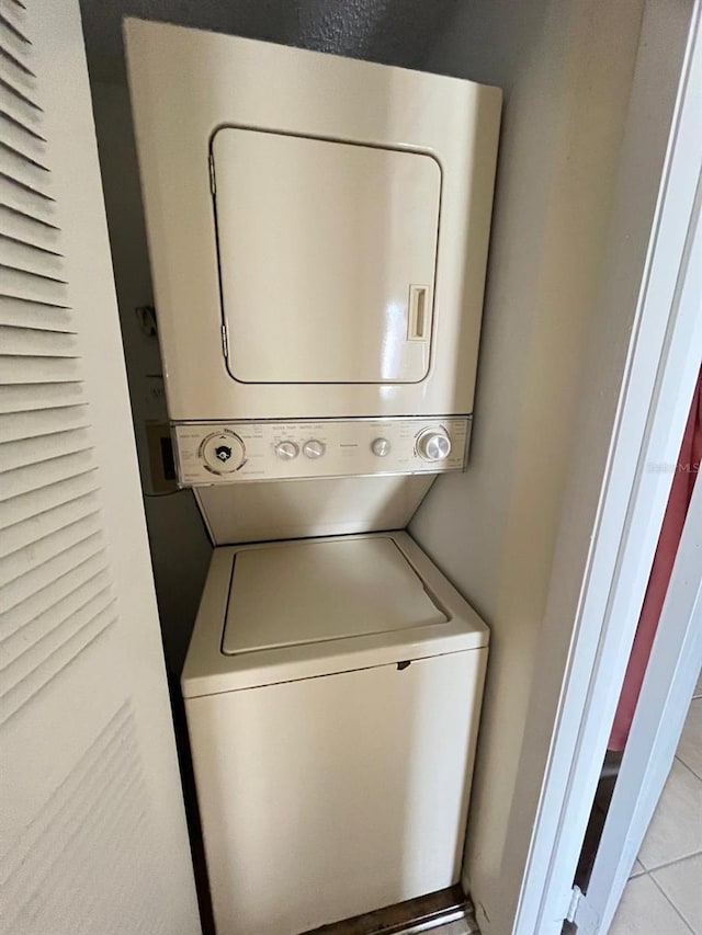 laundry room featuring estacked washer and dryer and light tile patterned floors