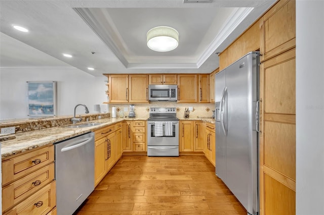 5275 S Atlantic Ave Unit 506, New Smyrna Beach, FL 32169 - kitchen featuring stainless steel appliances, light wood-type flooring, a sink, a tray ceiling, and light stone countertops