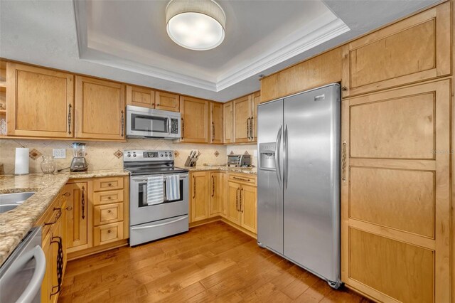 5275 S Atlantic Ave Unit 506, New Smyrna Beach, FL 32169 - kitchen featuring stainless steel appliances, a raised ceiling, light stone countertops, light wood-style floors, and backsplash