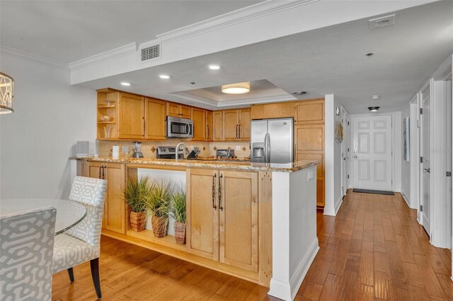 5275 S Atlantic Ave Unit 506, New Smyrna Beach, FL 32169 - kitchen featuring appliances with stainless steel finishes, open shelves, ornamental molding, wood finished floors, and a peninsula
