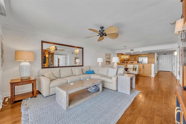 5275 S Atlantic Ave Unit 506, New Smyrna Beach, FL 32169 - living room featuring a ceiling fan, light wood finished floors, baseboards, and crown molding