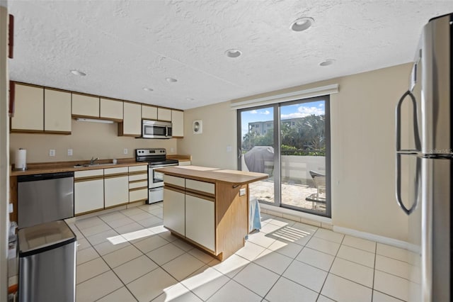 5275 S Atlantic Ave Unit 506, New Smyrna Beach, FL 32169 - kitchen featuring stainless steel appliances, wooden counters, a sink, light tile patterned floors, and baseboards