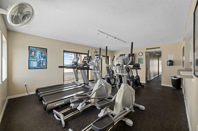 5275 S Atlantic Ave Unit 506, New Smyrna Beach, FL 32169 - exercise room with a textured ceiling, baseboards, and rail lighting