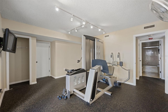5275 S Atlantic Ave Unit 506, New Smyrna Beach, FL 32169 - exercise area with a textured ceiling, baseboards, and rail lighting