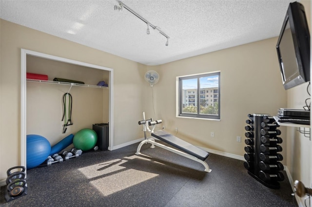 5275 S Atlantic Ave Unit 506, New Smyrna Beach, FL 32169 - exercise area featuring a textured ceiling, rail lighting, and baseboards