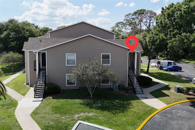 4704 Walden Cir Unit 21, Orlando, FL 32811 - view of side of property featuring stairway, a lawn, and roof with shingles