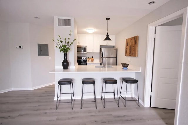 4704 Walden Cir Unit 21, Orlando, FL 32811 - kitchen with stainless steel appliances, a kitchen bar, electric panel, white cabinets, and light wood-style flooring