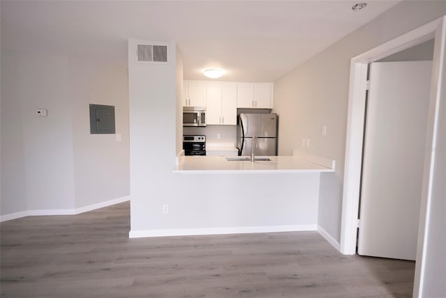4704 Walden Cir Unit 21, Orlando, FL 32811 - kitchen featuring stainless steel appliances, electric panel, white cabinetry, and wood finished floors
