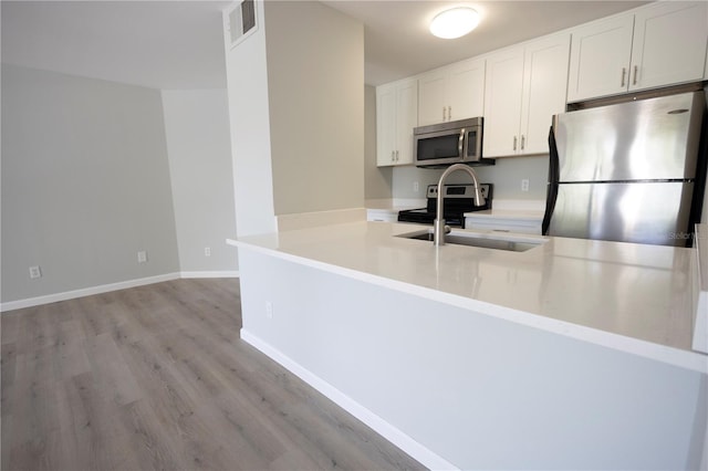 4704 Walden Cir Unit 21, Orlando, FL 32811 - kitchen with stainless steel appliances, a sink, light wood-style floors, white cabinetry, and light countertops