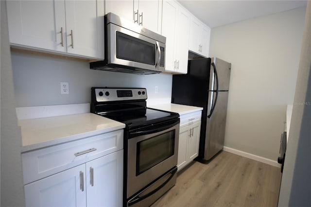 4704 Walden Cir Unit 21, Orlando, FL 32811 - kitchen with appliances with stainless steel finishes, light wood-type flooring, white cabinetry, and light countertops