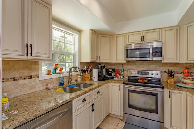 11435 Aries Dr, Orlando, FL 32837 - kitchen featuring appliances with stainless steel finishes, a sink, cream cabinets, light stone counters, and backsplash