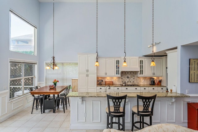 334 N Shadowbay Blvd, Longwood, FL 32779 - kitchen with a towering ceiling, a kitchen bar, pendant lighting, custom range hood, and glass insert cabinets