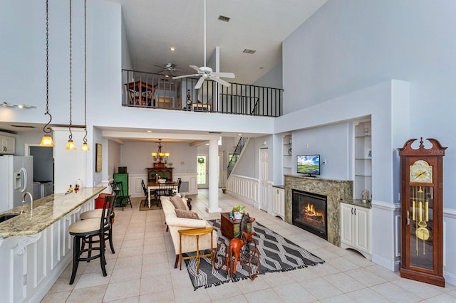334 N Shadowbay Blvd, Longwood, FL 32779 - living room featuring a fireplace, a high ceiling, a ceiling fan, light tile patterned floors, and a decorative wall