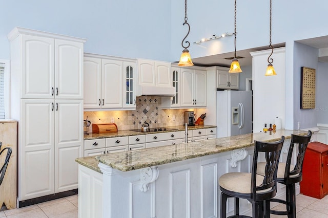 334 N Shadowbay Blvd, Longwood, FL 32779 - kitchen with white refrigerator with ice dispenser, light tile patterned floors, a towering ceiling, a breakfast bar area, and glass insert cabinets