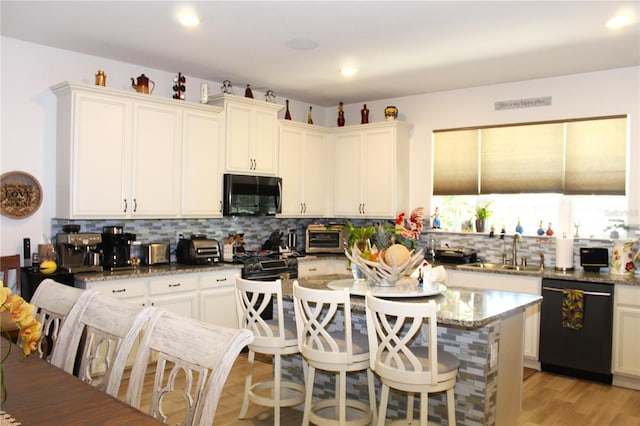 5897 Soter Ln, Windermere, FL 34786 - kitchen with black appliances, backsplash, a breakfast bar area, stone countertops, and a kitchen island