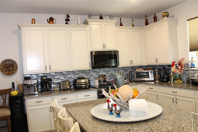5897 Soter Ln, Windermere, FL 34786 - kitchen featuring backsplash, light stone counters, black gas range oven, and white cabinets