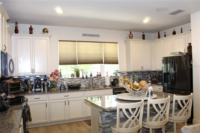 5897 Soter Ln, Windermere, FL 34786 - kitchen featuring a sink, black appliances, tasteful backsplash, dark stone counters, and recessed lighting