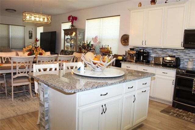 5897 Soter Ln, Windermere, FL 34786 - kitchen with range with two ovens, light wood-type flooring, a center island, white cabinetry, and light stone countertops