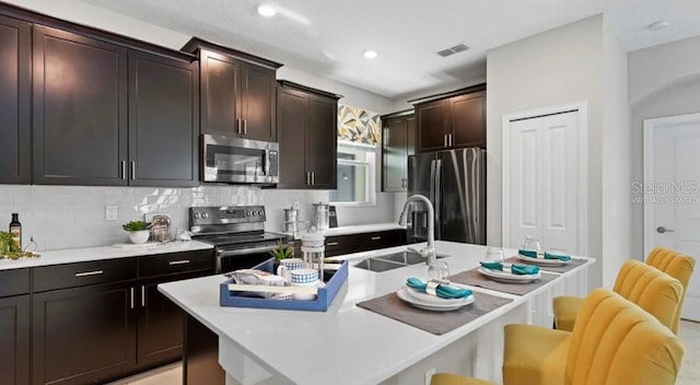 7876 Marlow Pl, Kissimmee, FL 34747 - kitchen with stainless steel appliances, a sink, a breakfast bar, tasteful backsplash, and light countertops