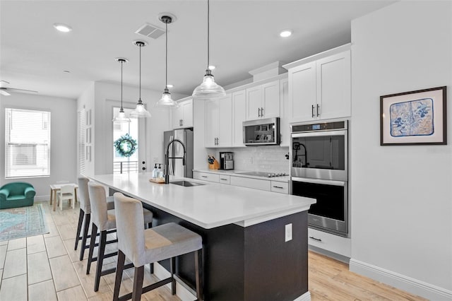 8460 Sperry St, Orlando, FL 32827 - kitchen with appliances with stainless steel finishes, a sink, an island with sink, tasteful backsplash, and white cabinetry