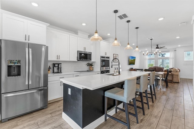 8460 Sperry St, Orlando, FL 32827 - kitchen with stainless steel appliances, a center island with sink, recessed lighting, light wood-style floors, and white cabinetry