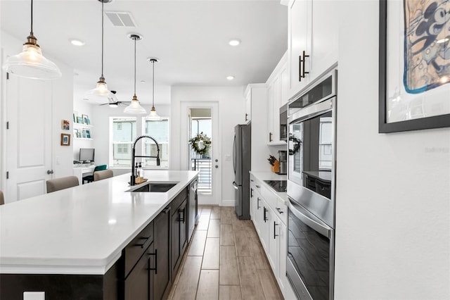 8460 Sperry St, Orlando, FL 32827 - kitchen with a sink, stainless steel appliances, an island with sink, light countertops, and white cabinetry