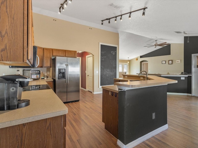 10247 Mason Loop, Clermont, FL 34711 - kitchen featuring appliances with stainless steel finishes, arched walkways, track lighting, brown cabinets, and ceiling fan